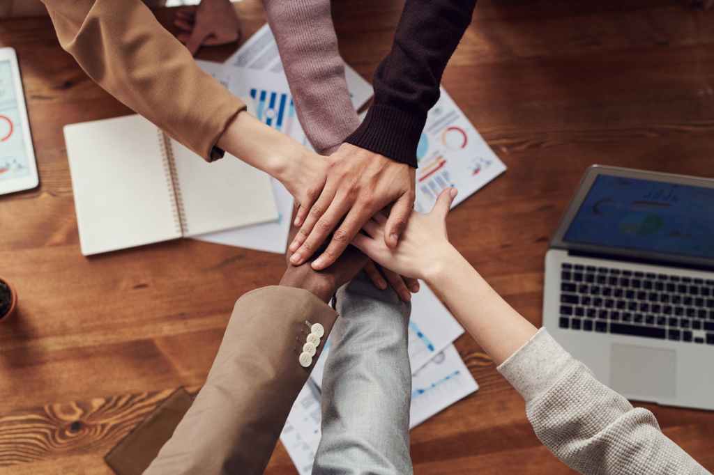Photo of people joining hands near wooden table