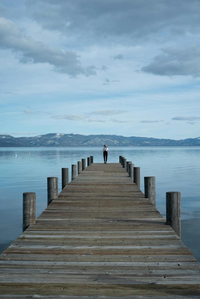Person standing on wooden dock looking at sea